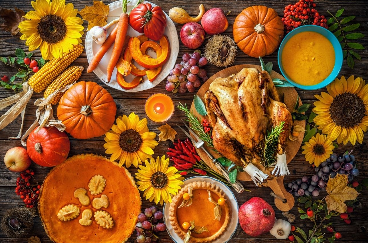A Thanksgiving feast with a variety of foods and flowers on a wooden table.